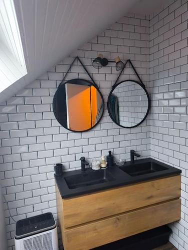 a bathroom with a sink and two mirrors on the wall at Maison de Charme à la campagne in Plumaugat