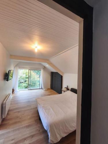 a bedroom with a white bed and a large window at Maison de Charme à la campagne in Plumaugat