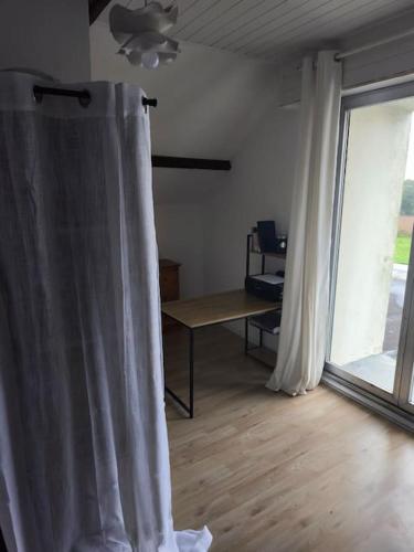a room with a white curtain and a table and a window at Maison de Charme à la campagne in Plumaugat