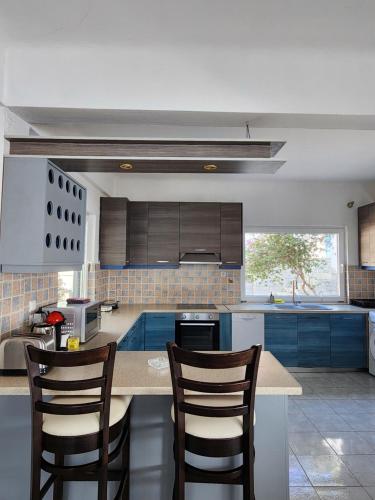 a kitchen with blue cabinets and a counter with chairs at Villa Nikolitsa with private beach in Megara