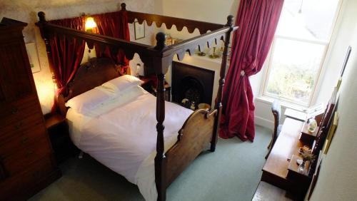 a bedroom with a large wooden bed with white sheets at Greystones B&B in Kingussie