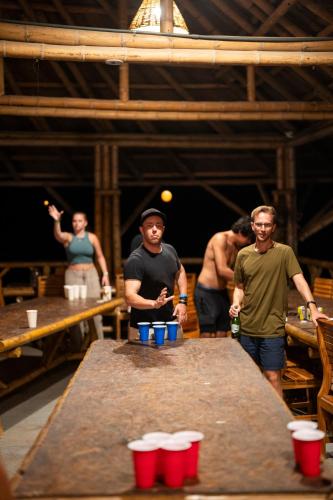 a group of men standing around a table with red cups at The Journey Hostel in Los Naranjos