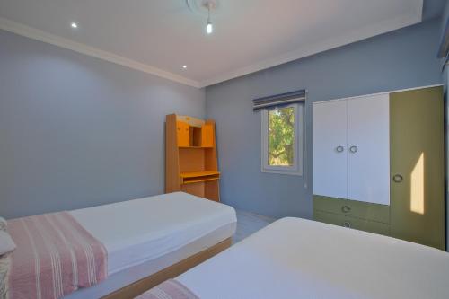 een kleine slaapkamer met twee bedden en een raam bij Avci Villa-Fethiye 3+1 in Garden with Private Pool, 10 minutes to the beach in Fethiye