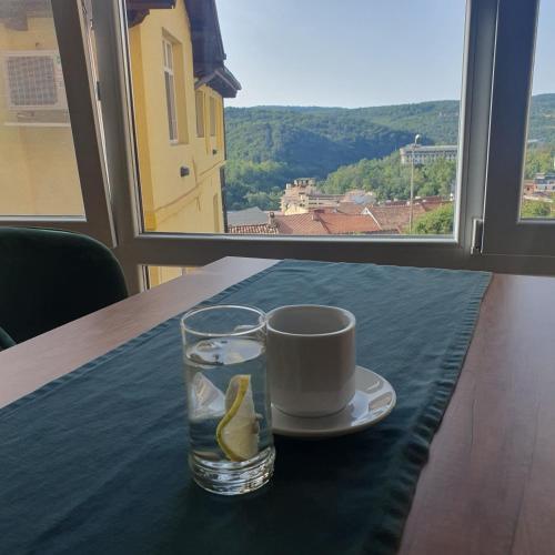 a cup of coffee and a lemon on a table with a window at Guest House Gurkov in Veliko Tŭrnovo