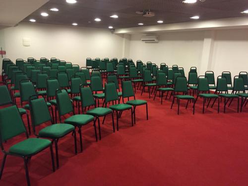 an empty room with green chairs on a red carpet at Reserve Hotel in Surubim