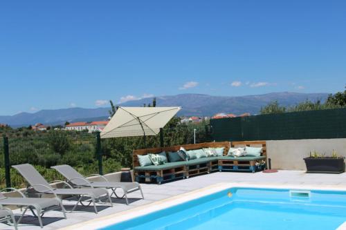 a patio with a pool and chairs and a couch at As Tílias Homely 46 in Carvalhal