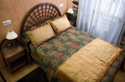 a bedroom with a bed with a quilt on it at Casa Mameleiro e Casa Kintal in A Pontenova