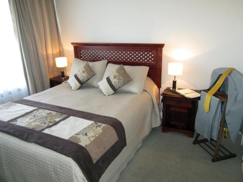 ein Schlafzimmer mit einem Bett mit zwei Lampen und einem Telefon in der Unterkunft Lobato Apartments in Santiago