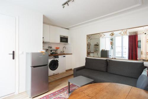 Il comprend un salon avec un canapé gris et une cuisine. dans l'établissement Cosy Flat 30m2 Paris Centre, à Paris