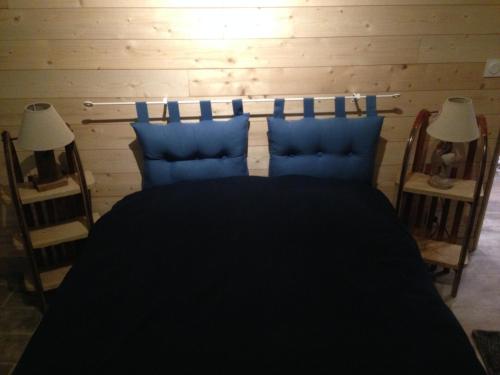 a bedroom with a black bed with two blue pillows at Villa Boston in La Bourboule