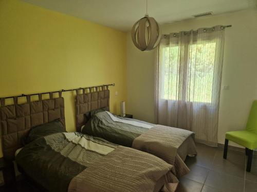 - une chambre avec deux lits et une chaise verte dans l'établissement Le MAS DISON, à Euzet