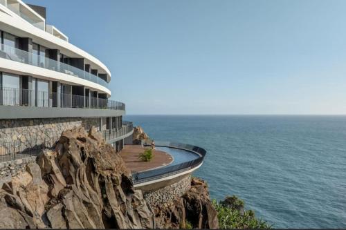 a building on a cliff next to the ocean at Varandas do Atlântico in Câmara de Lobos