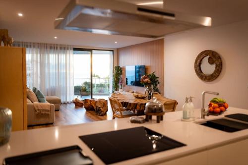 a kitchen with a table and a living room at Varandas do Atlântico in Câmara de Lobos