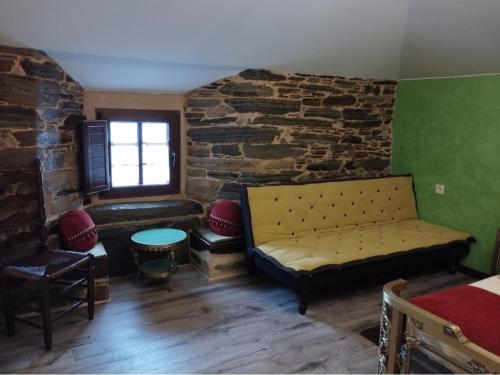 a living room with a couch and a stone wall at Casa Mameleiro e Casa Kintal in A Pontenova