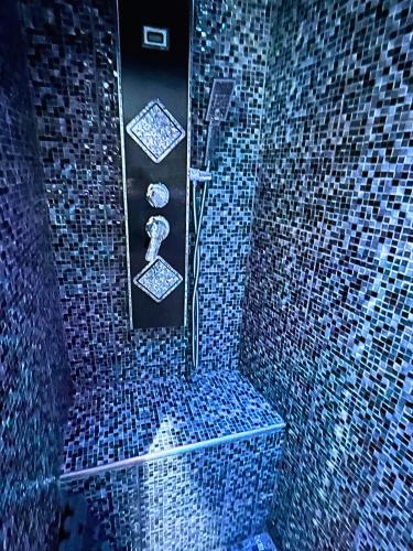 a bathroom with a shower with blue mosaic tiles at Le Saphir Spa & Jacuzzi in Manosque