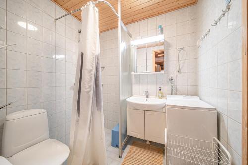 a white bathroom with a toilet and a sink at Kiiruna by Aavalevi Holidays, Levi Center in Levi