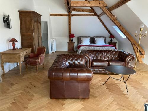 a living room with a leather couch and a bed at Casa La Palma Le 48 in Soissons