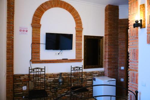 a living room with a tv and a brick wall at Janashia Hotels in Tbilisi City