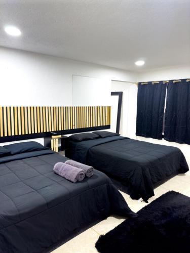 瓦哈卡市Alojamiento CARLO Y ABRIL的卧室里有两张床，铺着黑色床单，挂着黑色窗帘。