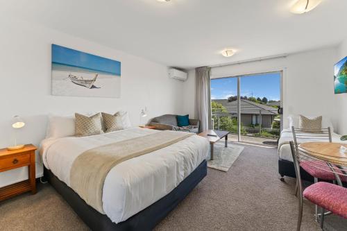 a bedroom with a large bed and a table and chairs at Greens Motel in Nelson
