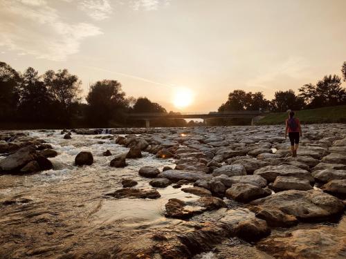 a man walking across a rocky river at sunset at Green Street Hideaway in Šempeter v Savinjski Dolini