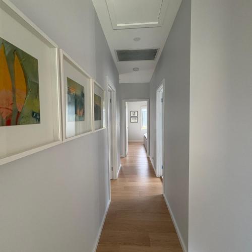 a hallway with white walls and paintings on the walls at Goolwa Beach Pavilion in Goolwa South