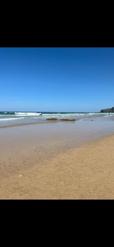 a sandy beach with the ocean in the background at Cousins beach house Three bedroom lodge St Minver in Wadebridge