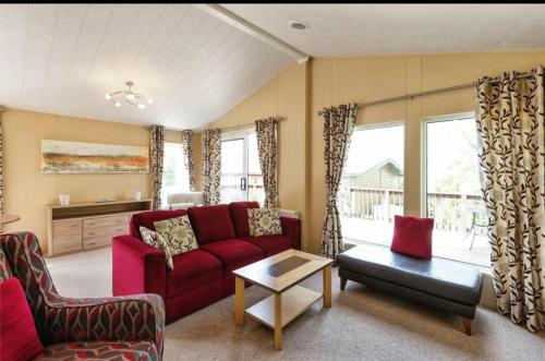 a living room with a red couch and a table at Cousins beach house Three bedroom lodge St Minver in Wadebridge