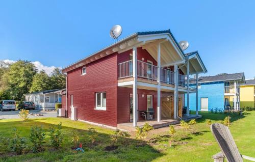 a red house with a balcony on a yard at Seehund Xl in Süssau