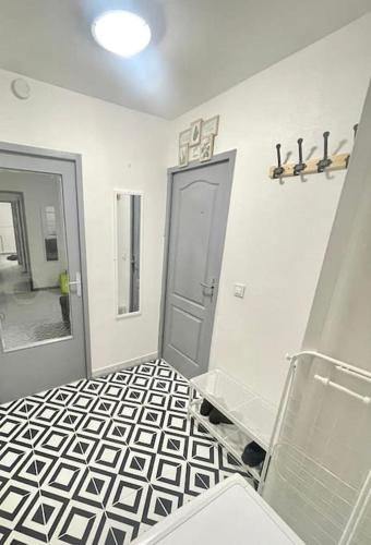 La salle de bains est pourvue d'une porte et de carrelage noir et blanc. dans l'établissement Appartement spacieux et moderne, à Vaulx-en-Velin