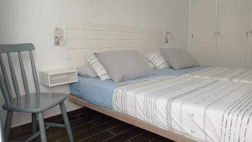 a bedroom with a bed with a chair and a chair at Buena Fuerte Apartamentos Mari Giuli in Tarajalejo