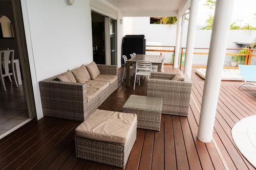 a porch with a couch and a table and chairs at La case à Nath - Piscine chauffée et jacuzzi in Saint-Pierre