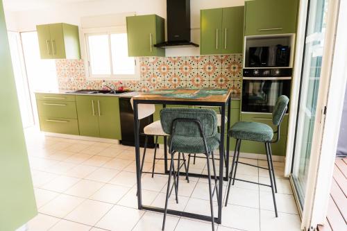 a kitchen with green cabinets and bar stools at La case à Nath - Piscine chauffée et jacuzzi in Saint-Pierre
