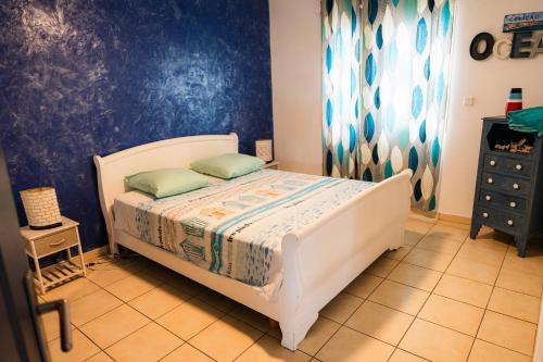 a bedroom with a bed and a blue wall at La case à Nath - Piscine chauffée et jacuzzi in Saint-Pierre