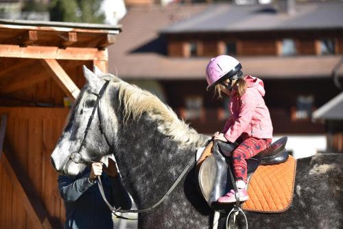 a little girl riding on the back of a horse at Obenfigerhof in Kals am Großglockner