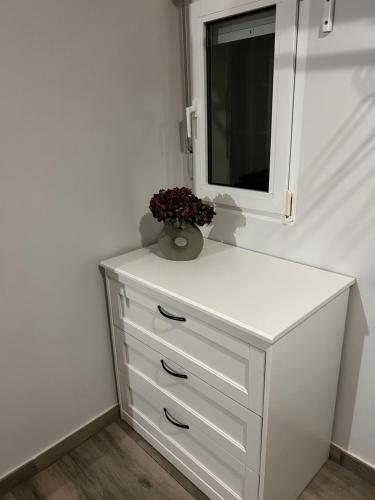 a white dresser with a mirror and a vase of flowers at Paraje Sanchazurra in Vallejera de Riofrío