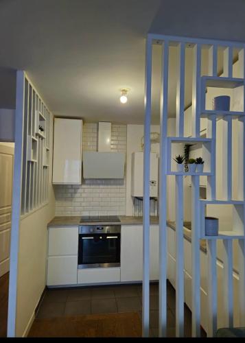 une petite cuisine avec des placards blancs et une échelle bleue dans l'établissement Le Valmy, à Colombes