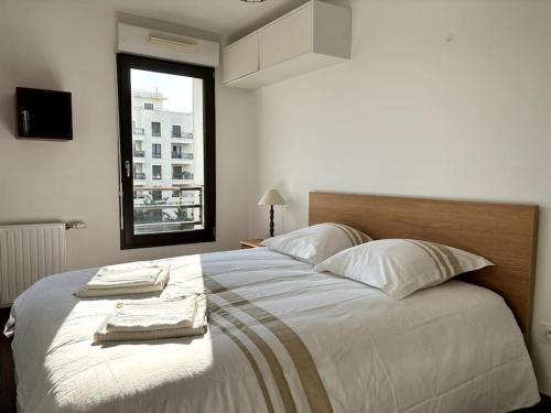 une chambre avec un grand lit avec deux serviettes dessus dans l'établissement Appartement familial - Proche Versailles, à Saint-Cyr-lʼÉcole