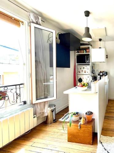 Il comprend une cuisine avec une grande fenêtre et un réfrigérateur blanc. dans l'établissement Lovely Paris appartment, à Paris