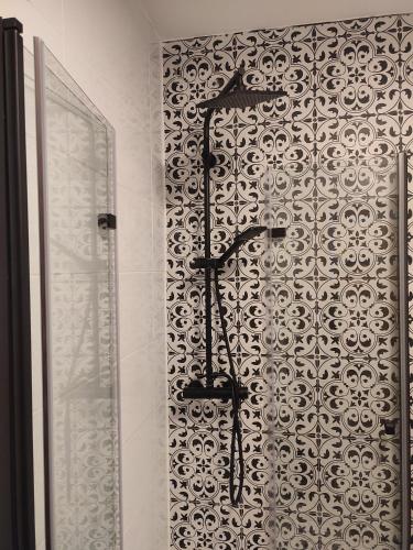 a shower in a bathroom with a patterned wall at Lawendowo- sauna, basen, domki w ogrodzie i apartamenty w kamienicy in Sandomierz