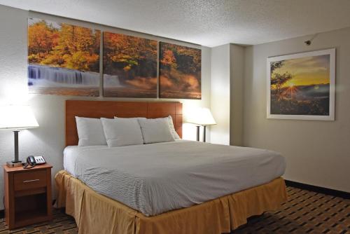 a bed in a hotel room with paintings on the wall at Days Inn by Wyndham Lebanon in Lebanon