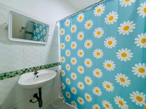 Baño con lavabo blanco y margaritas en la pared en SERISIAM Apartments, en Hat Yai