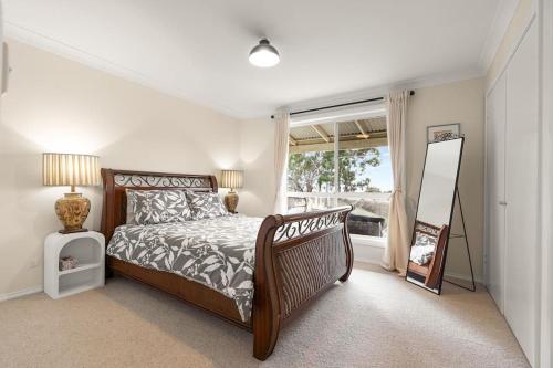 a bedroom with a bed and a mirror and a window at Cooinda, A 3 Bedroom Home Near Mayfield Garden in Oberon