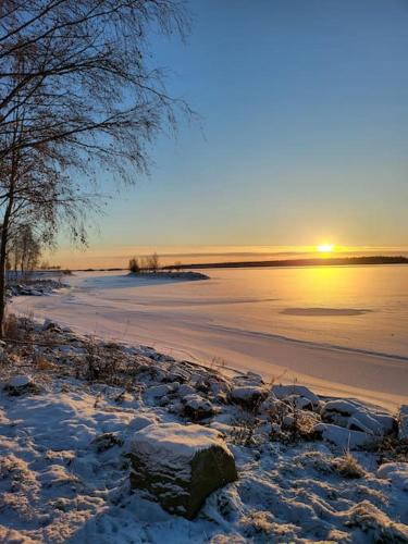 a frozen lake with the sun setting on the horizon at 40-Apartment in Kemi city center , balcony and free parking in Kemi
