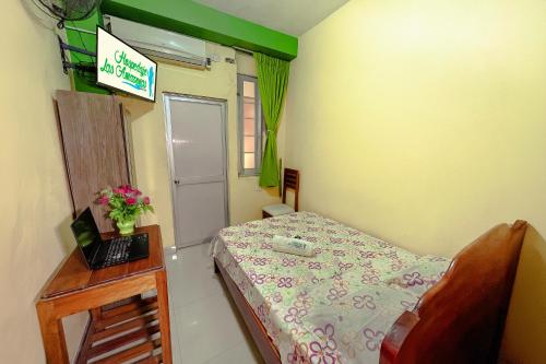 a small bedroom with a bed and a desk with a laptop at Hospedaje Las Amazonas in Iquitos