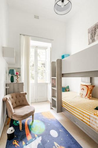a bedroom with a bunk bed and a chair at "Spirit of Malta" Historic Maltese Townhouse by the sea in Sliema
