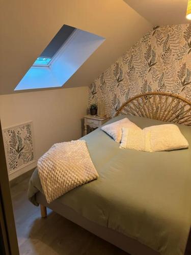 une chambre avec un grand lit avec une lucarne dans l'établissement La maison de Charlotte, à Auvers-sur-Oise