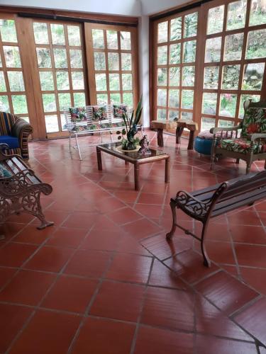 a large room with benches and tables and windows at Hotel Campestre Villa Nico in Bochalema