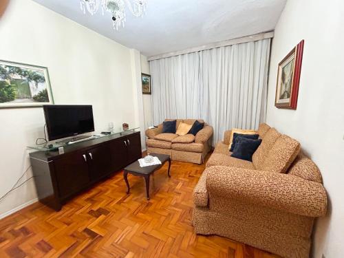 a living room with two chairs and a flat screen tv at Apartamento 2 quartos no Centro de Terê in Teresópolis