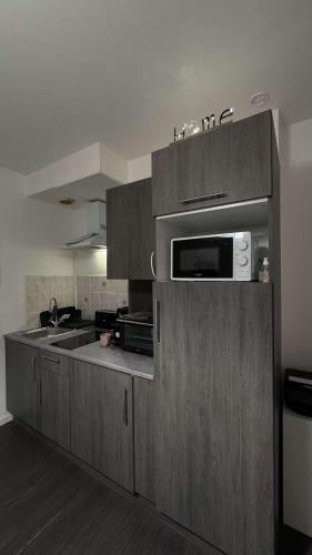 a kitchen with wooden cabinets and a microwave at Appartement cosy et chaleureux avec vue sur nature in Liancourt